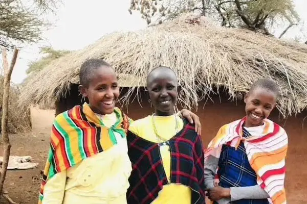 Our purpose in Empowering Maasai girls standing in front of a boma, highlighting the cultural and purposeful travel experience.