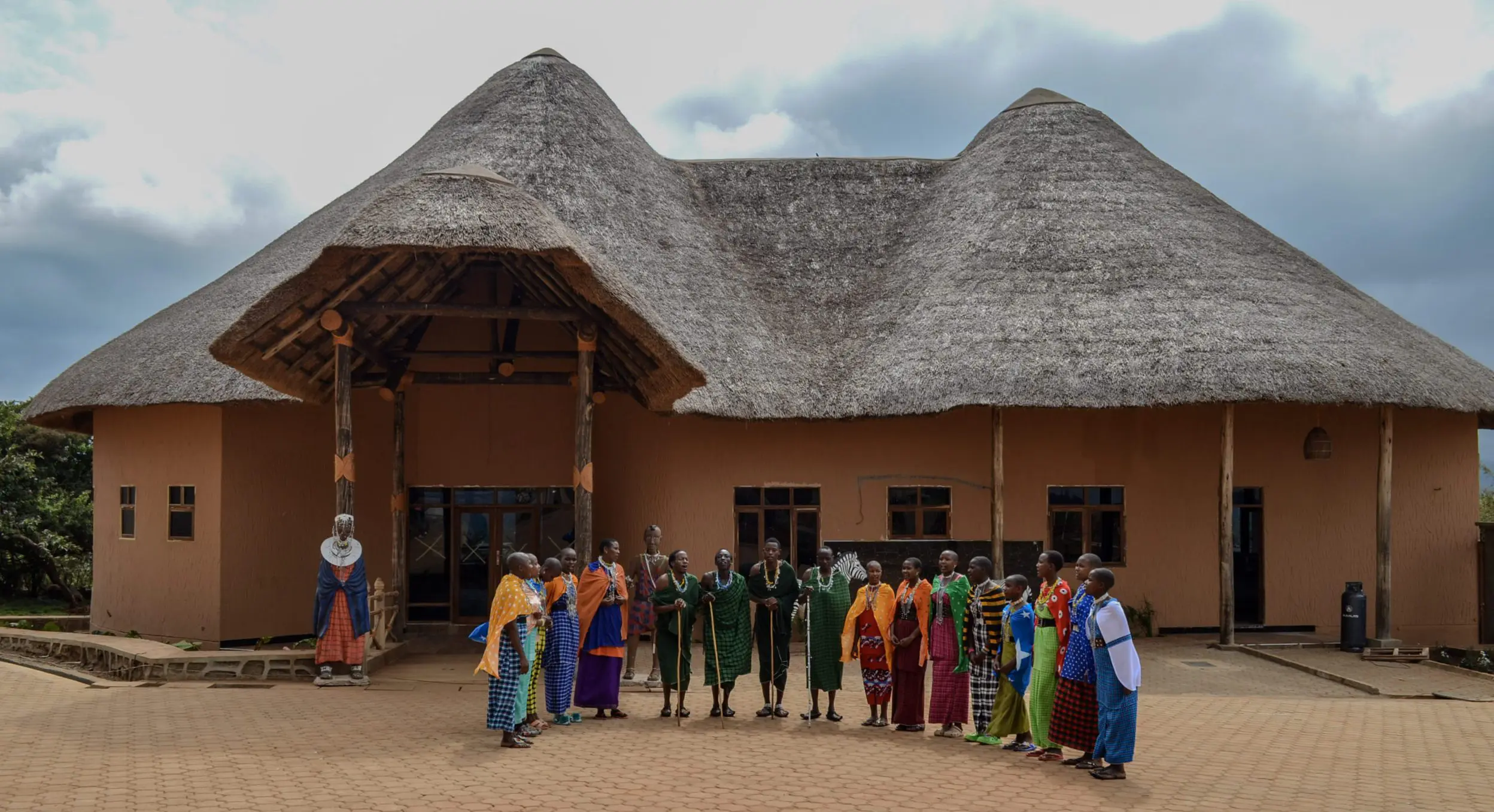 Traditional maasai gathering near thatched building.