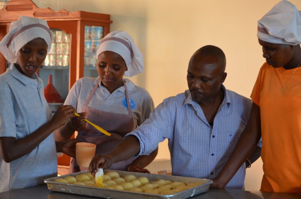 young maasai women learning how to bake with maasai ecolodge chef