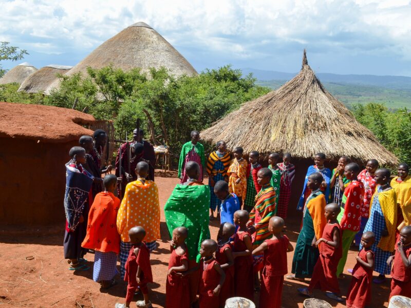 Maasai students from rescue center gathered in front of traditional bomas at maasai culture center